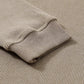 Close-up of a beige long-sleeve sweatshirt with ribbed cuffs and textured fabric.