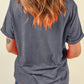 Back view of a woman wearing a gray short-sleeved t-shirt and blue jeans.