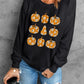 A woman wears a black long-sleeve sweatshirt with pumpkin graphics and ripped jeans.