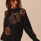 Black knit sweater with orange pumpkin embroidery.