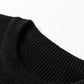 Close-up of a black ribbed knit sweater with a round neck.