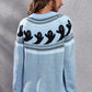 A woman models a light blue, long-sleeve sweater with a ghost pattern on the back.