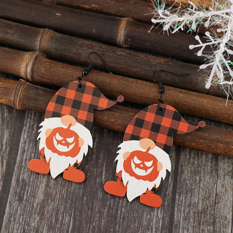 A pair of wooden dangle earrings shaped like gnomes with plaid hats and pumpkin bodies.