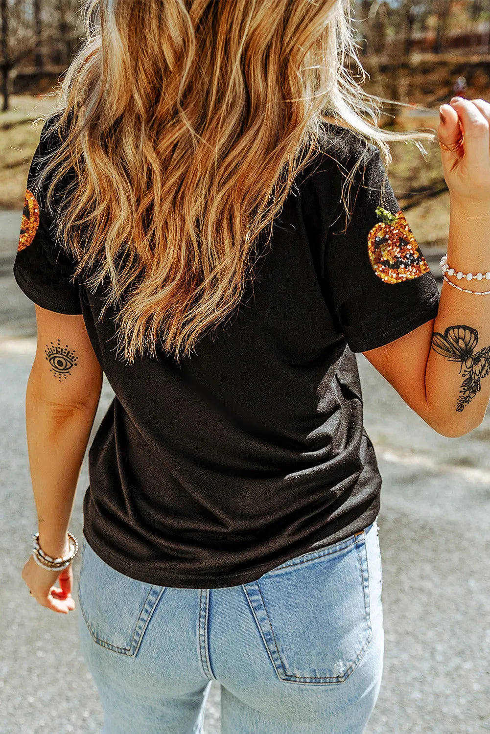 Black short-sleeve t-shirt with sequin pumpkins on the shoulders.