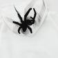 White oversized hoodie with a black spider graphic on the hood.