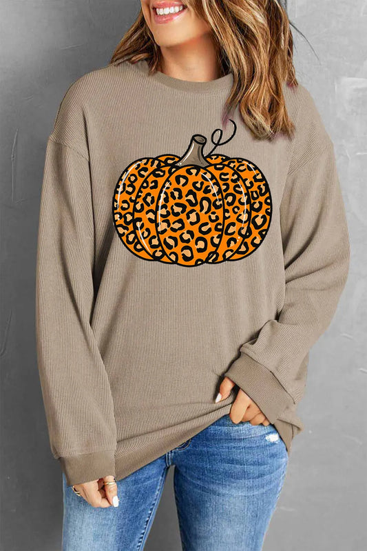 A woman wears a long-sleeve, round-neck sweatshirt with a leopard print pumpkin graphic.