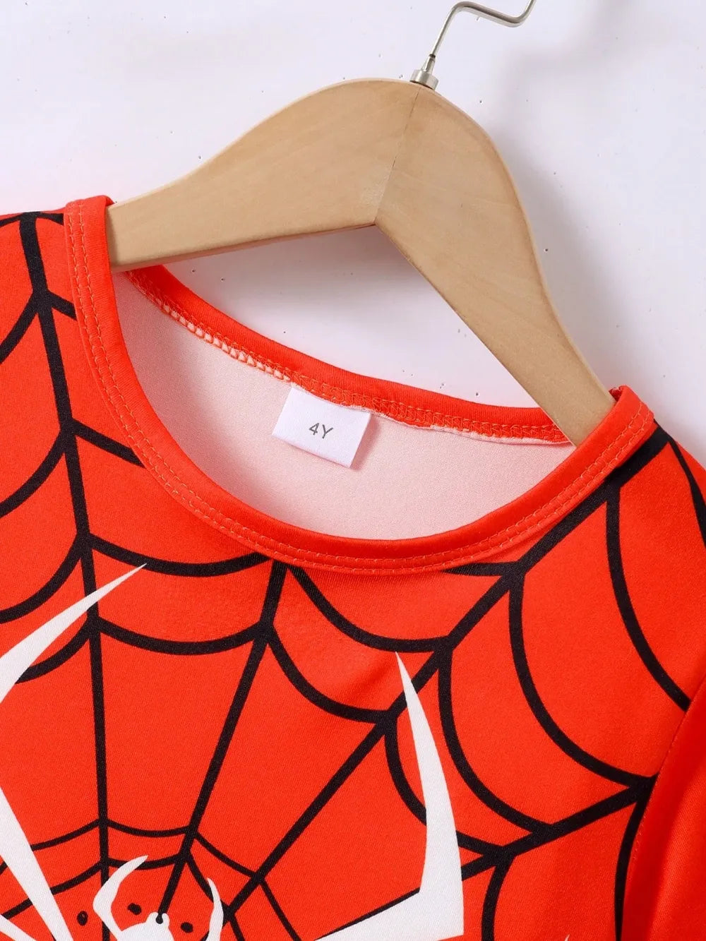 A red spiderweb-patterned children's t-shirt with a "4Y" size tag on a hanger.