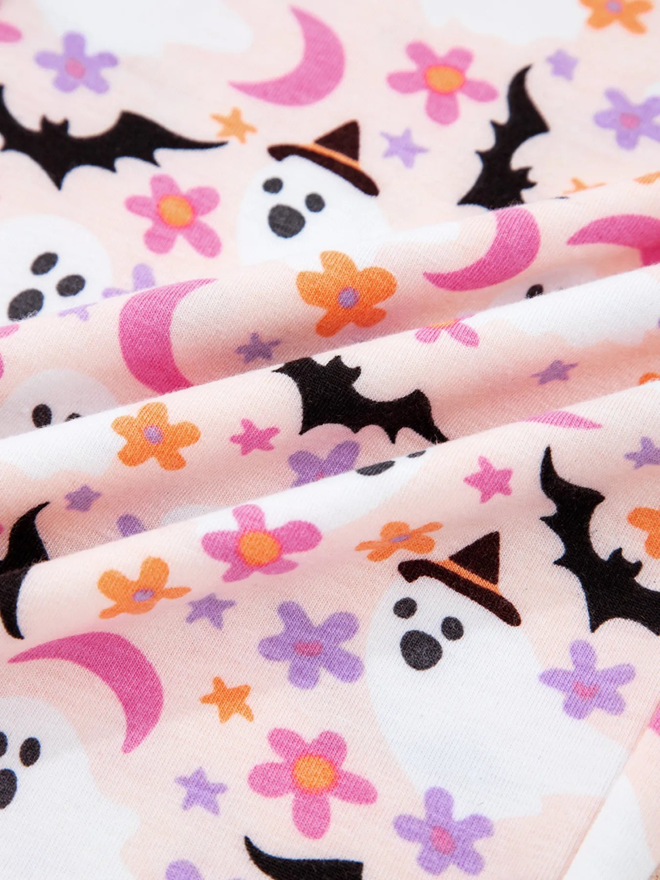 Pink fabric with a Halloween ghost, bat, moon, and flower print.