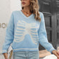 A woman wears a light blue v-neck sweater with a white skeleton rib cage pattern.