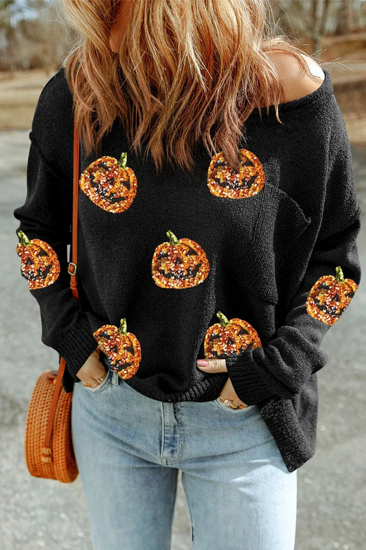 A woman wears a black knit top with sequin pumpkins and light wash jeans.