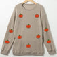 A beige long-sleeve sweatshirt with multiple orange pumpkin appliques.