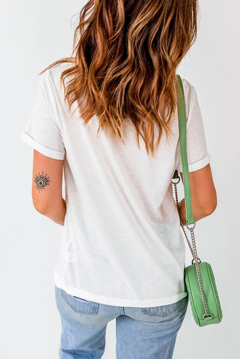 A woman from behind wears a white short-sleeve t-shirt and light-wash jeans.