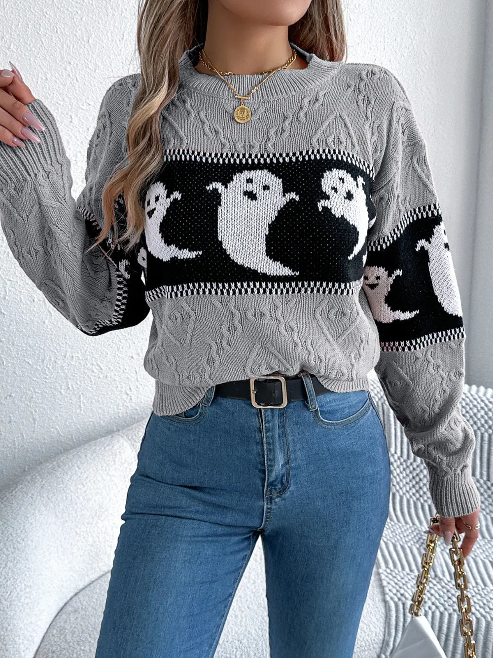 A woman wears a gray long-sleeve sweater with a black and white ghost pattern.