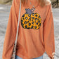 A woman wears an orange corduroy sweatshirt with a leopard print pumpkin design.