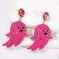 Two pink, ghost-shaped dangle earrings with black faces and light blue accents.
