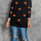 A woman wears a black long-sleeve sweatshirt with pumpkin designs and ripped jeans.