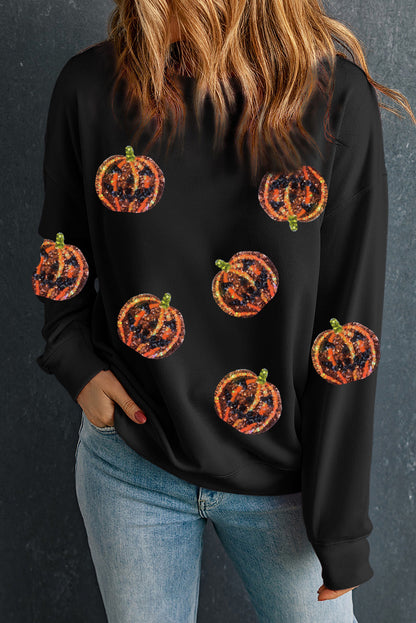 A woman wears a black dropped shoulder sweatshirt with multiple pumpkin designs.