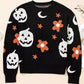 Black long-sleeve sweater with white pumpkins, orange flowers, and stars.
