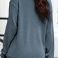 A woman from behind wears a blue ribbed long-sleeve sweatshirt and black pants.