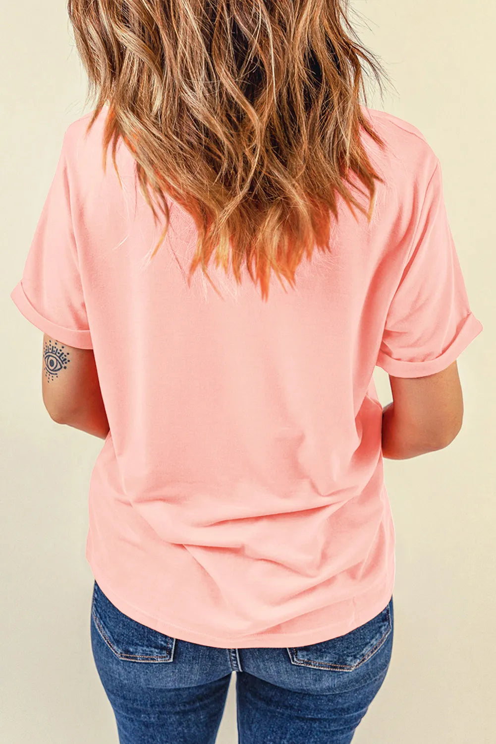 Back view of a woman wearing a pink short-sleeve t-shirt and blue jeans.