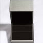 An open, empty, dark gray jewelry box with a light gray lid.
