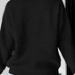 A woman from behind wears a black long-sleeve round-neck sweater and denim shorts.