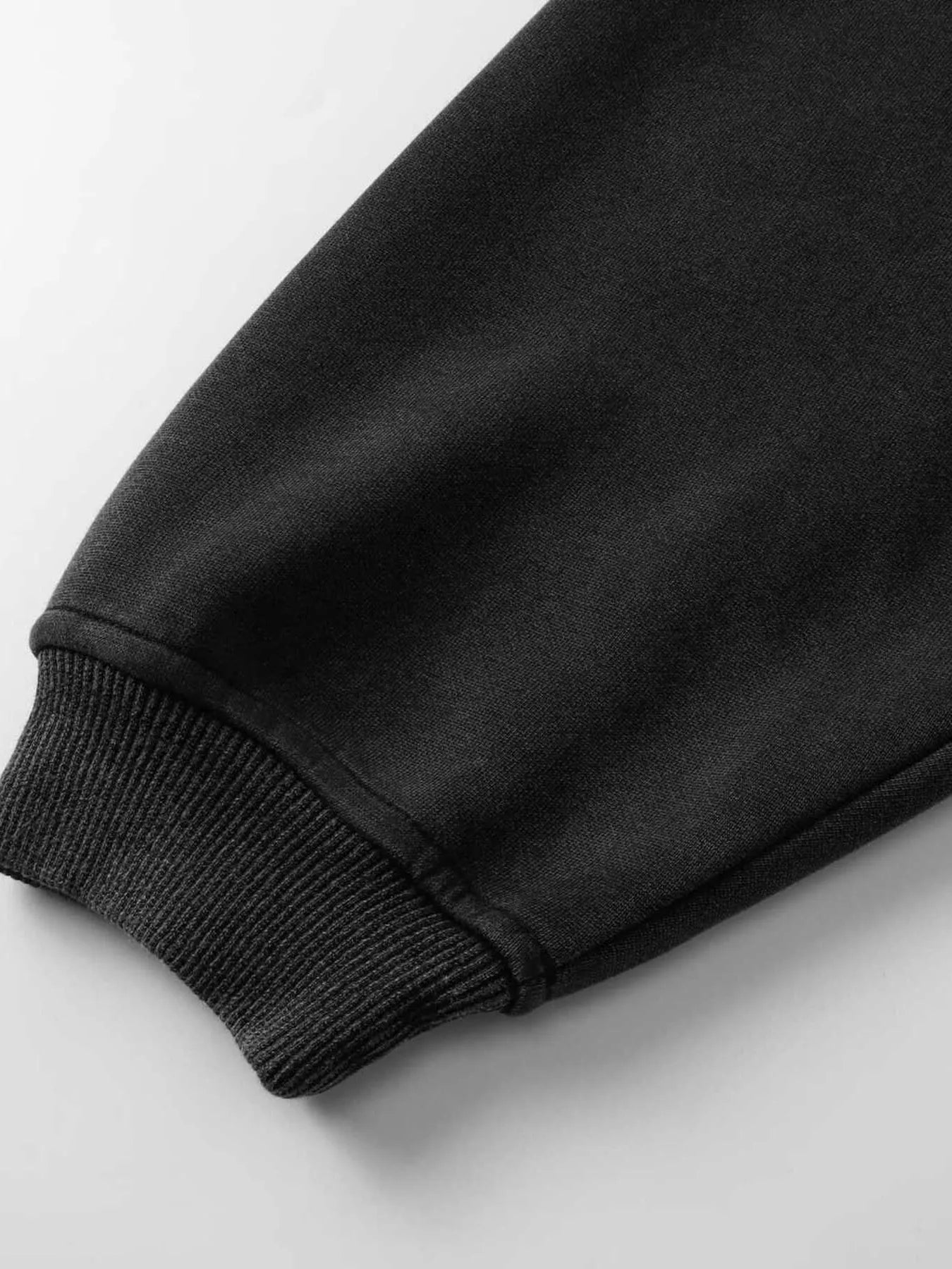 Close-up of a black hoodie sleeve with a ribbed cuff.