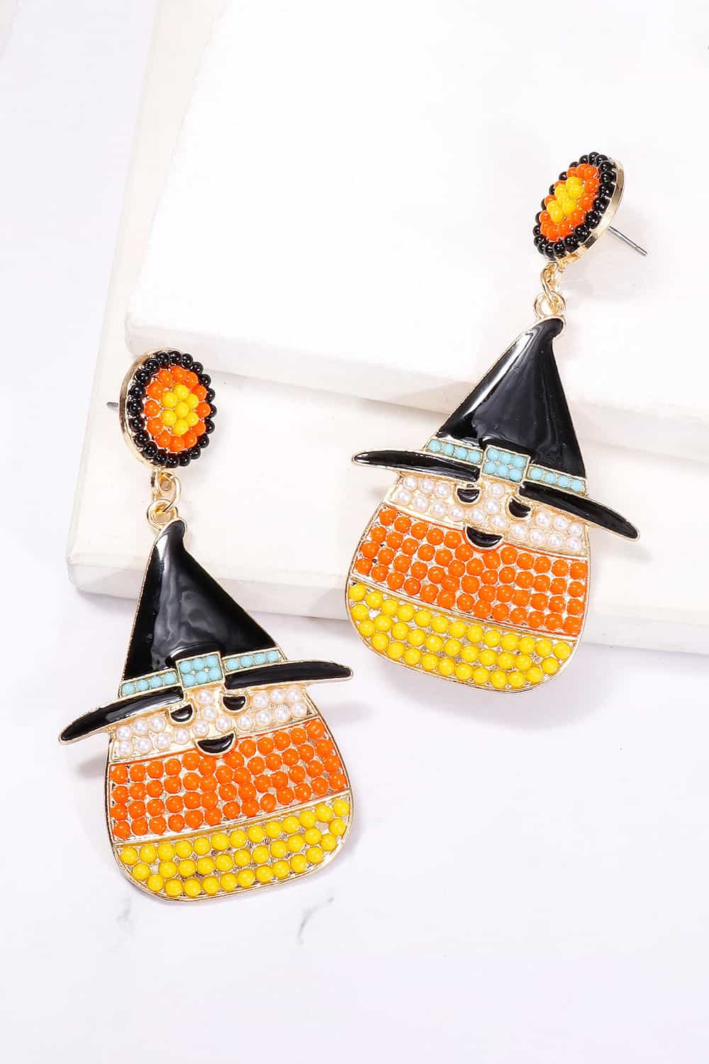 Two dangle earrings feature a witch's hat on a candy corn-shaped body with a smiling face.