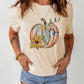 A woman wears a cream-colored t-shirt with a colorful pumpkin graphic.