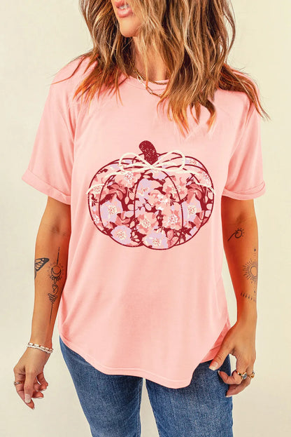 A woman wears a pink t-shirt with a floral pumpkin graphic.