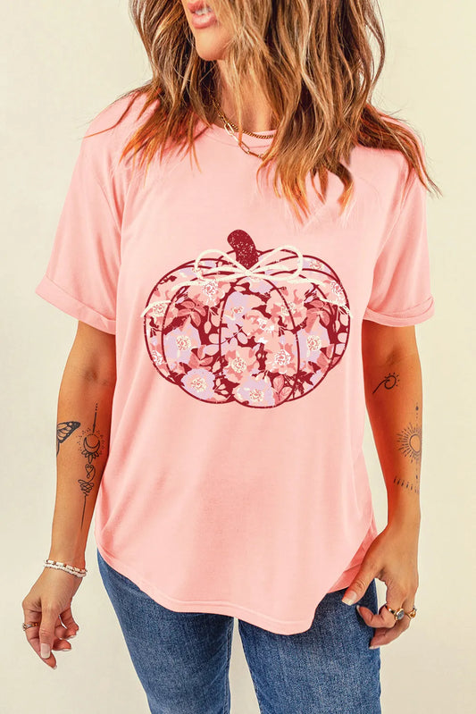 A woman wears a pink t-shirt with a floral pumpkin graphic.
