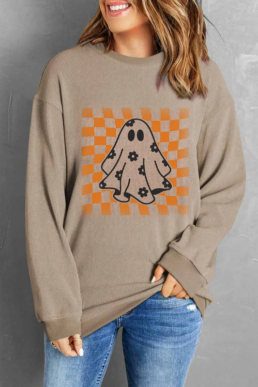A woman wears a ghost print long sleeve sweatshirt with a checkered background.