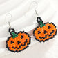 Two beaded Halloween pumpkin earrings with orange, black, and green beads.