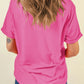 Back view of a woman wearing a pink t-shirt and blue jeans.