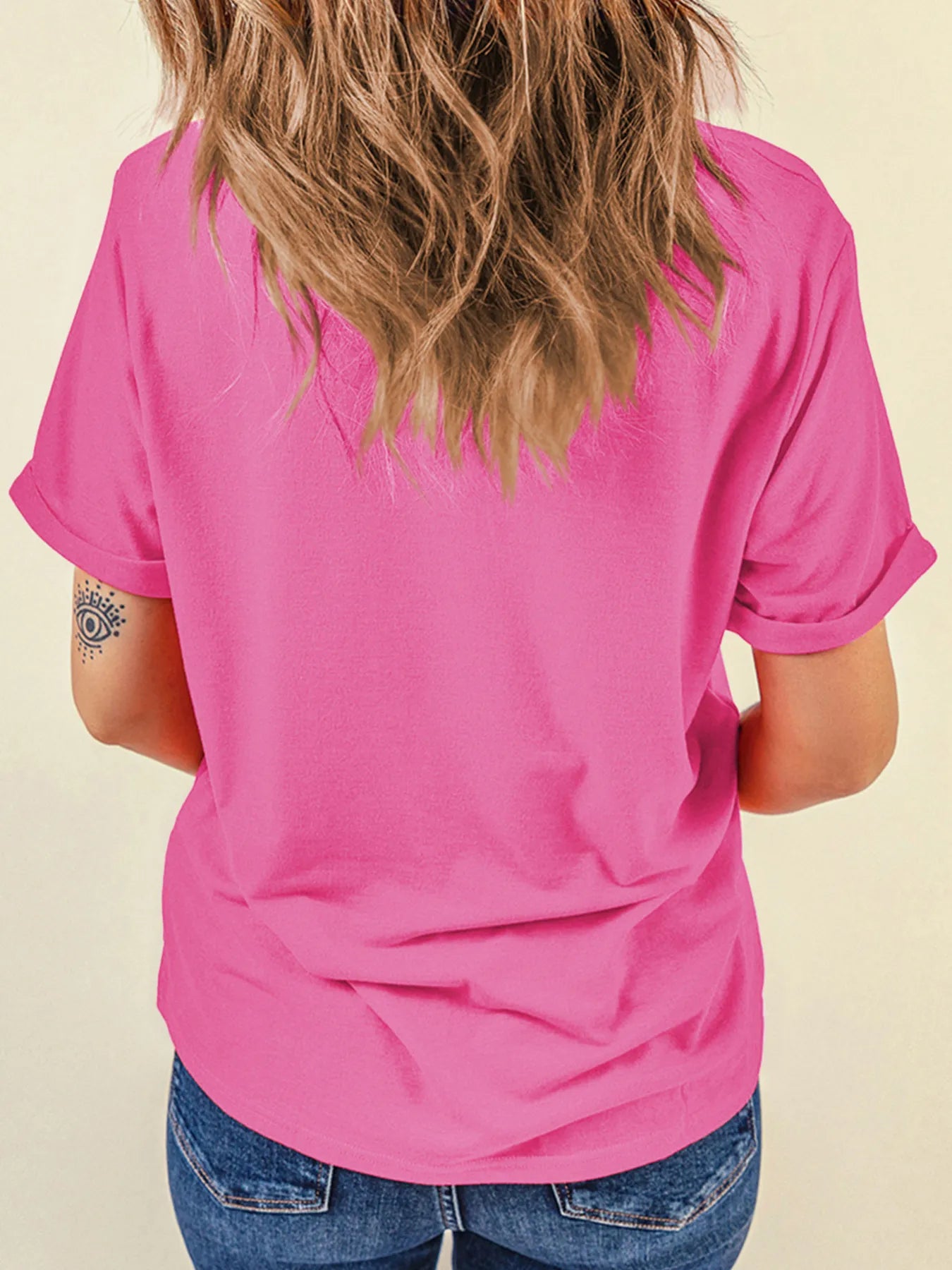 Back view of a woman wearing a pink t-shirt and blue jeans.