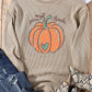 Pumpkin graphic round neck long sleeve sweatshirt with distressed jeans and snakeskin boots.