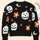 Black long-sleeve sweater with white pumpkins, orange flowers, and moons.