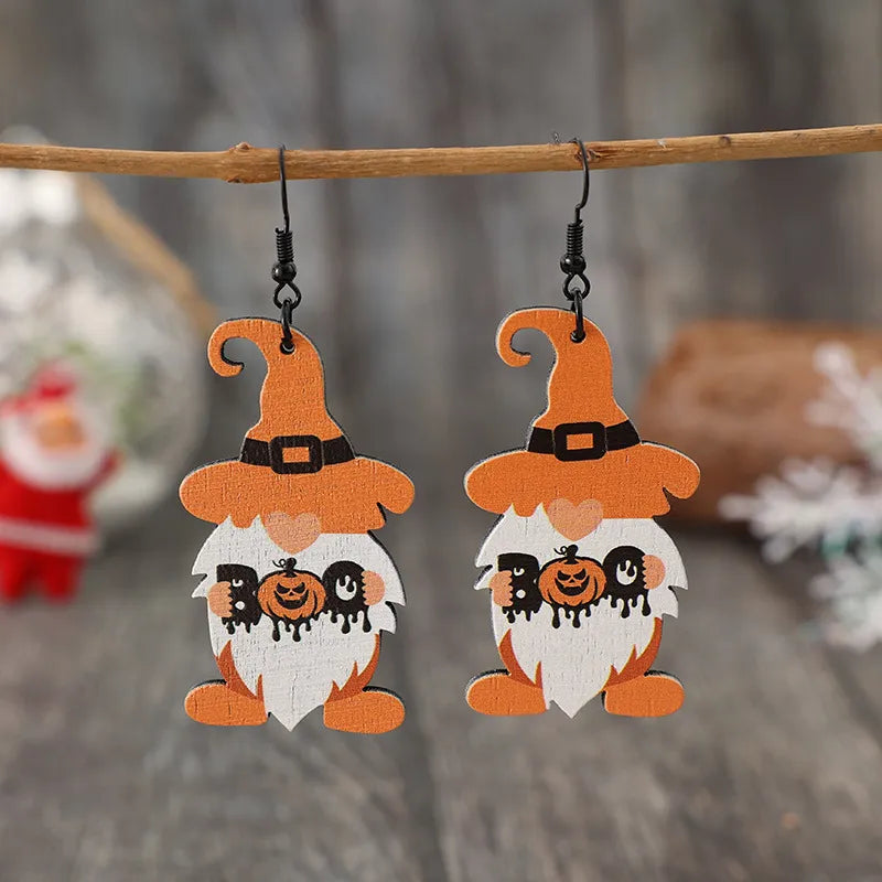 A pair of wooden dwarf pumpkin dangle earrings with orange hats and white beards.