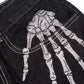 Black denim jeans with a white embroidered skeleton hand on the upper thigh.