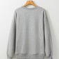 Gray long-sleeved sweatshirt with ribbed cuffs and hem, hanging on a wooden hanger.