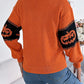 Orange long-sleeve sweater with black pumpkin designs on the sleeves.