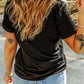 A woman from behind wears a black short-sleeve t-shirt and light blue jeans.