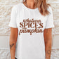 A woman wears a white graphic tee that says "WHATEVER SPICES YOUR PUMPKIN".