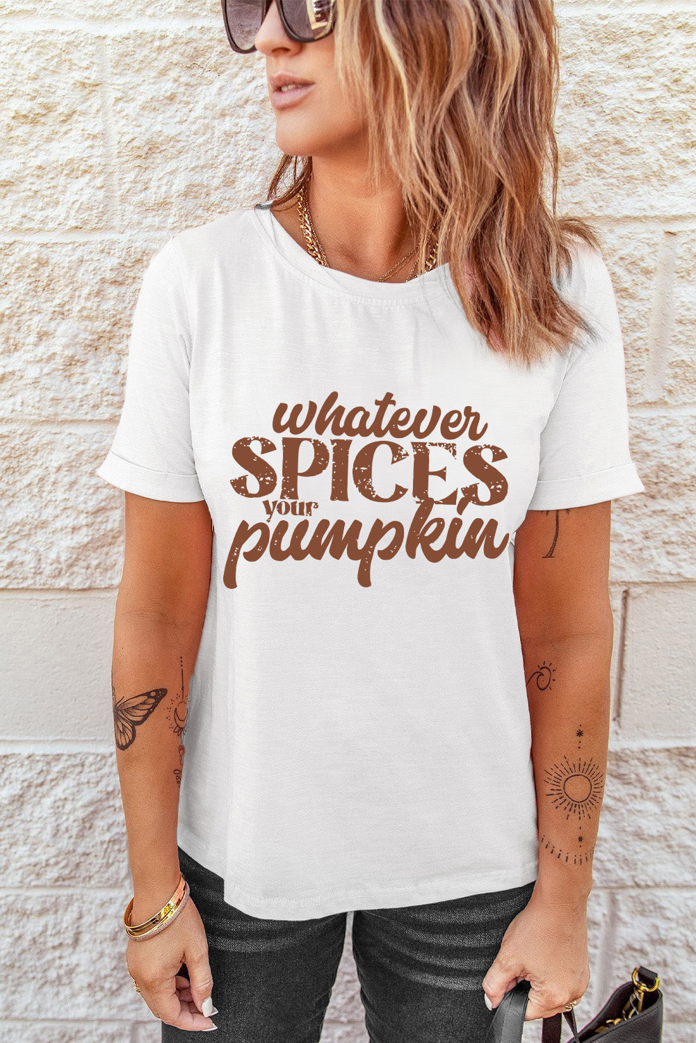 A woman wears a white graphic tee that says "WHATEVER SPICES YOUR PUMPKIN".