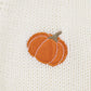 A close-up of a white knit cardigan with an embroidered orange pumpkin.