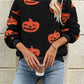 Fuzzy black sweater with orange pumpkin designs, worn with blue jeans.