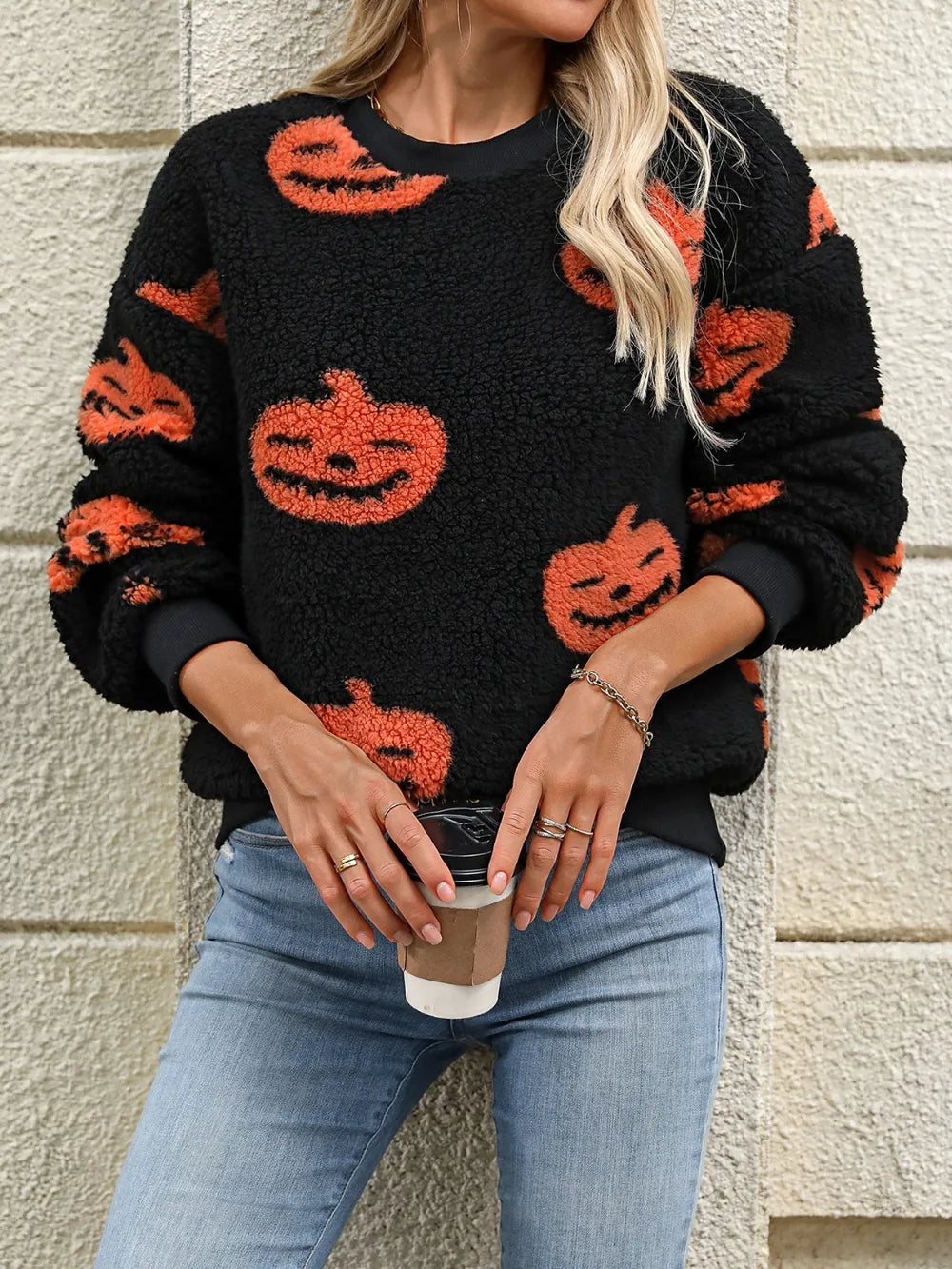 Fuzzy black sweater with orange pumpkin designs, worn with blue jeans.