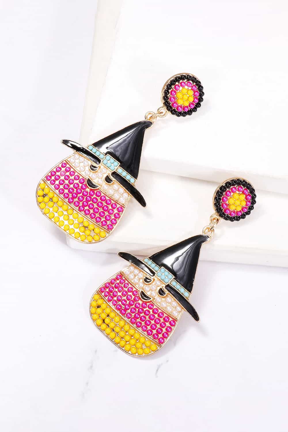 Two witch's hat dangle earrings with colorful synthetic pearls are displayed on a white surface.