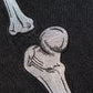 Close-up of embroidered skeleton bones on black denim.