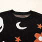 Black long sleeve sweater with white moons, orange stars, and orange flowers.